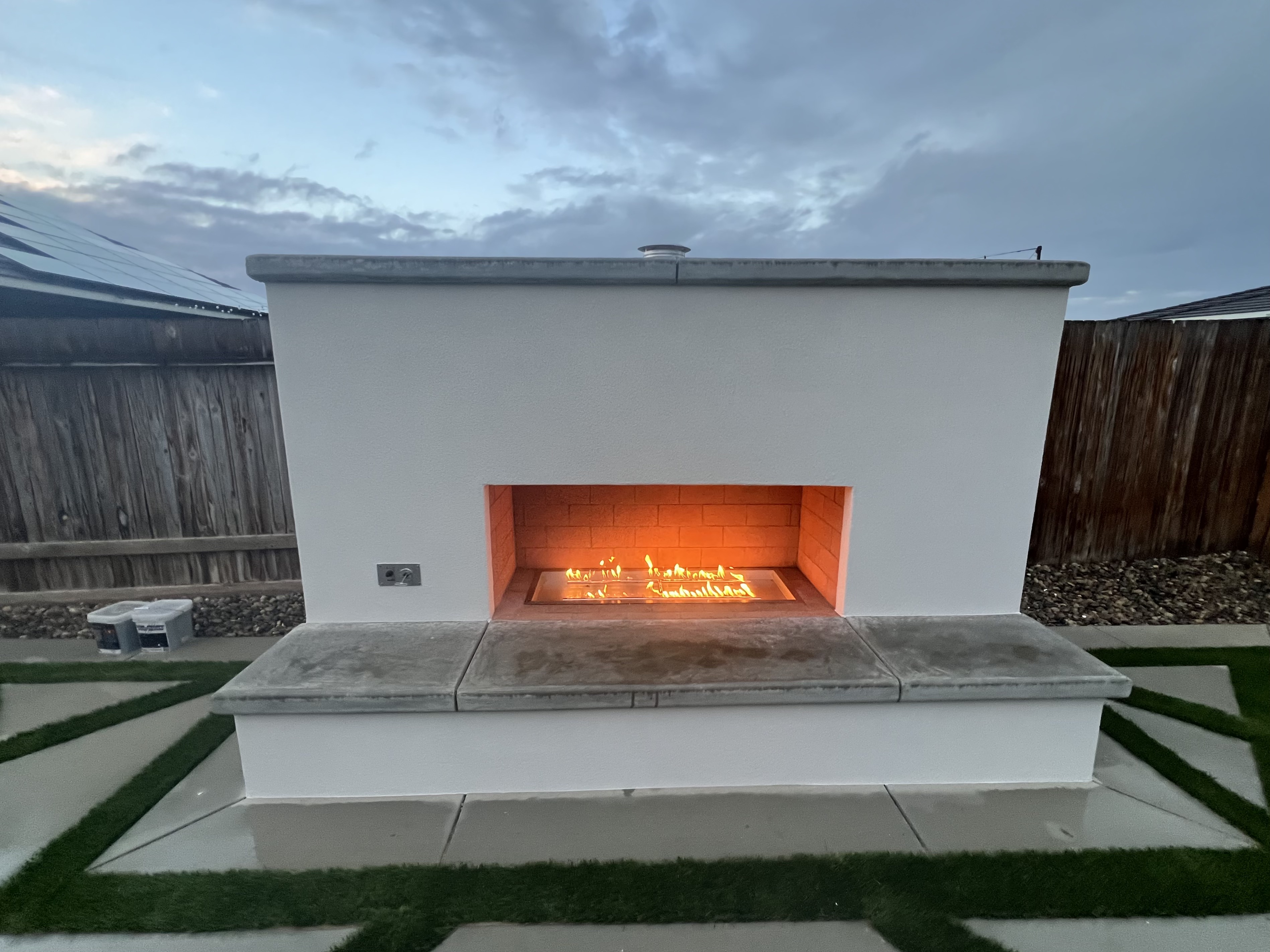 Modern outdoor fireplace with artificial turf and concrete accents